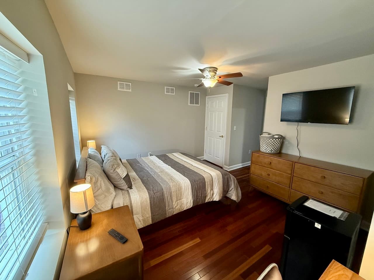 Furnished bedroom with hardwood floors, TV, and mini fridge